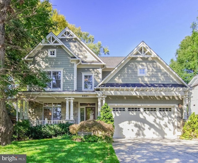 craftsman inspired home with a front lawn, covered porch, and a garage