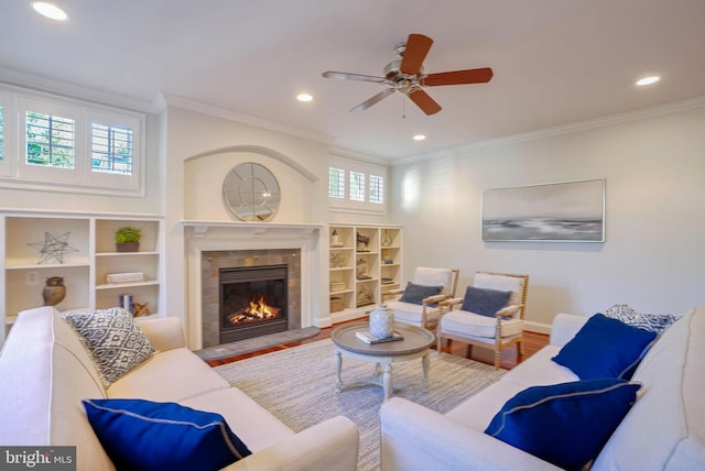 living room featuring wood-type flooring, ceiling fan, ornamental molding, and a premium fireplace