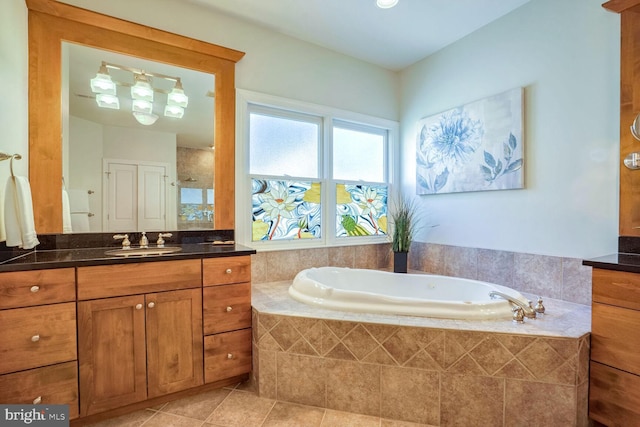 bathroom with tile patterned flooring, vanity, and a relaxing tiled tub