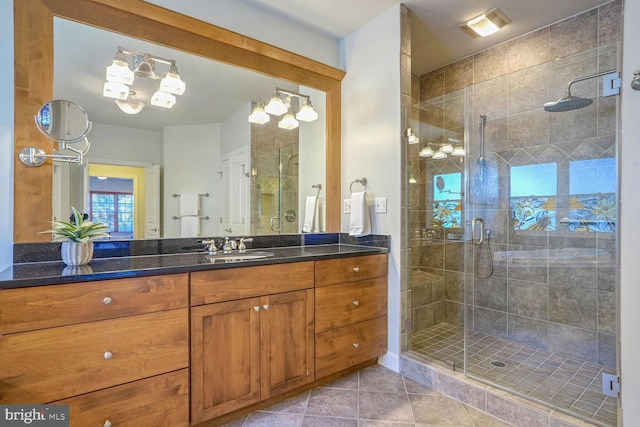 bathroom featuring tile patterned flooring, vanity, a chandelier, and a shower with door