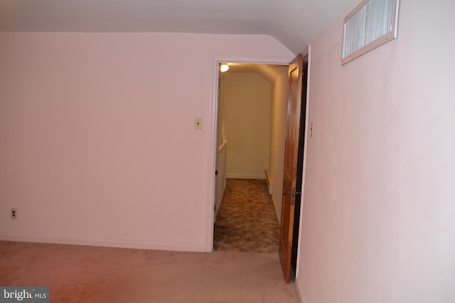 corridor with vaulted ceiling and light colored carpet