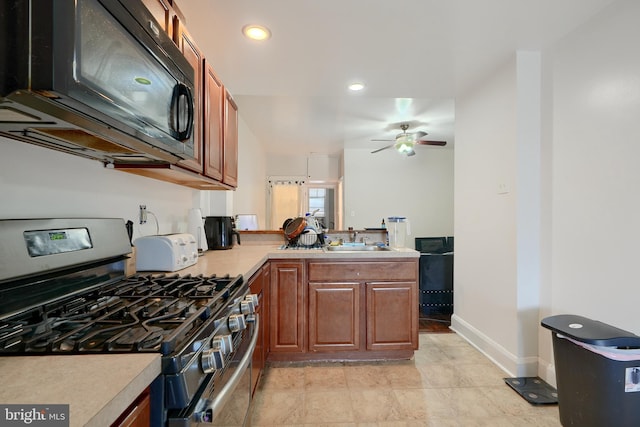 kitchen with ceiling fan, kitchen peninsula, sink, and stainless steel gas range