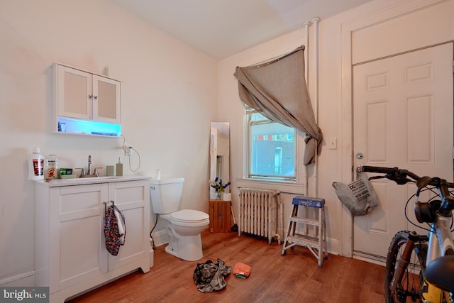 bathroom featuring radiator heating unit, vanity, toilet, and hardwood / wood-style floors