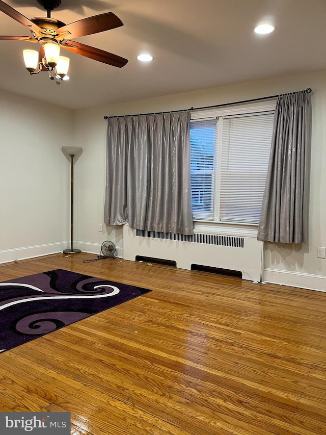 interior space with hardwood / wood-style flooring, ceiling fan, and radiator heating unit