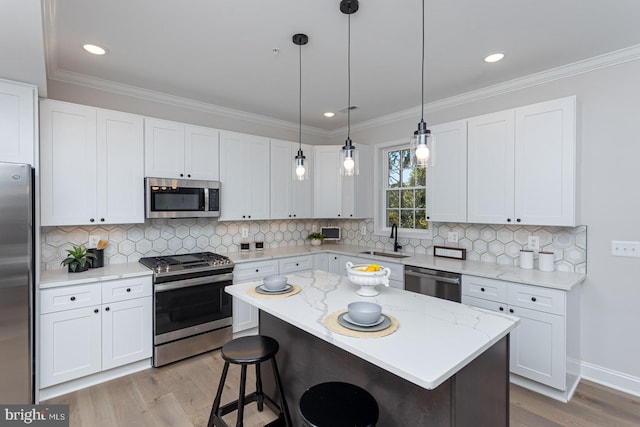 kitchen with appliances with stainless steel finishes, pendant lighting, white cabinetry, and a kitchen island