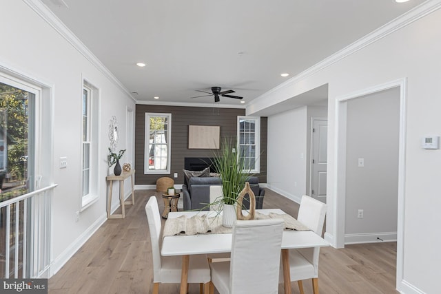 dining space featuring light hardwood / wood-style floors, plenty of natural light, a large fireplace, and ornamental molding