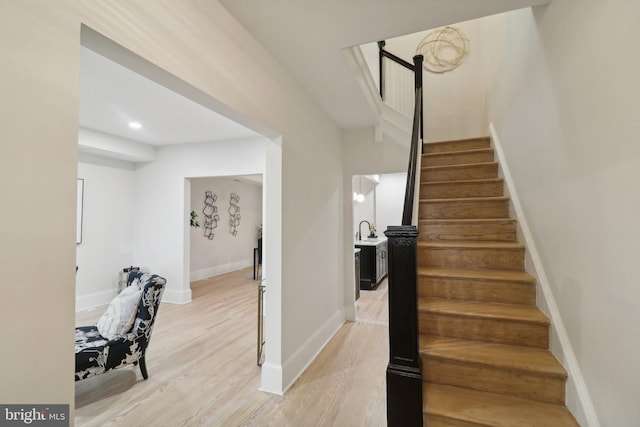 staircase with hardwood / wood-style flooring and sink