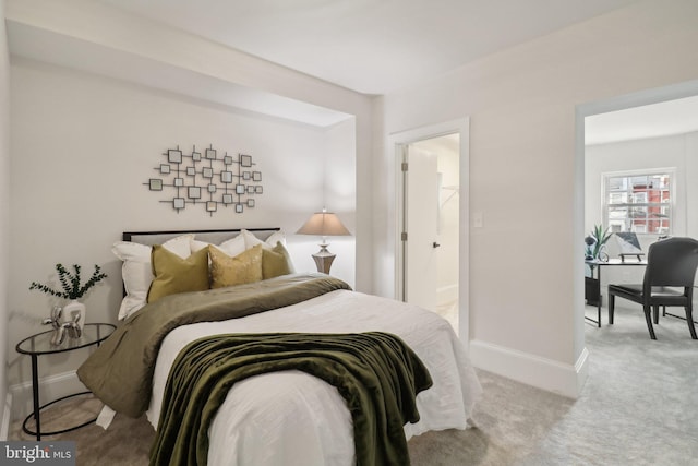 bedroom featuring light carpet and a walk in closet