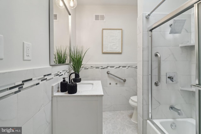 full bathroom featuring vanity, toilet, tile walls, and tiled shower / bath combo