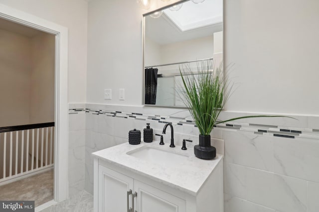 bathroom featuring a shower with curtain, vanity, tile walls, and a skylight