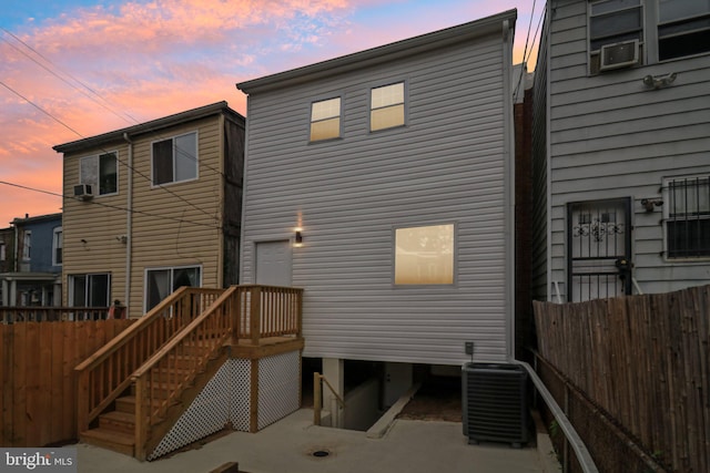 back house at dusk featuring cooling unit and central AC