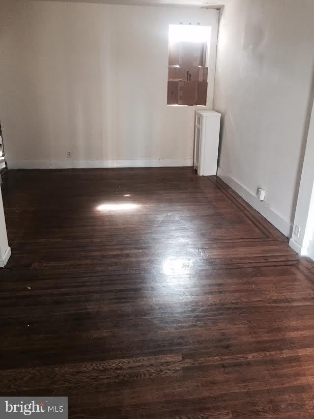 empty room with dark hardwood / wood-style flooring and radiator heating unit