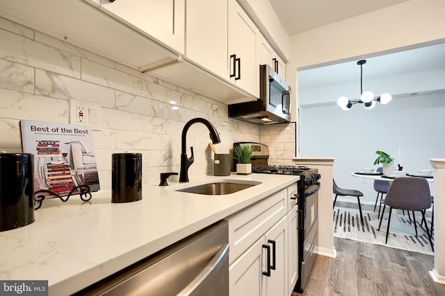 kitchen with pendant lighting, sink, appliances with stainless steel finishes, tasteful backsplash, and white cabinetry