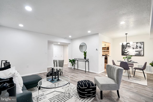 living room with hardwood / wood-style flooring, a textured ceiling, and an inviting chandelier