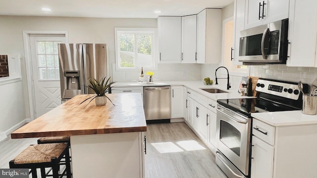 kitchen with a center island, a breakfast bar, white cabinetry, appliances with stainless steel finishes, and sink