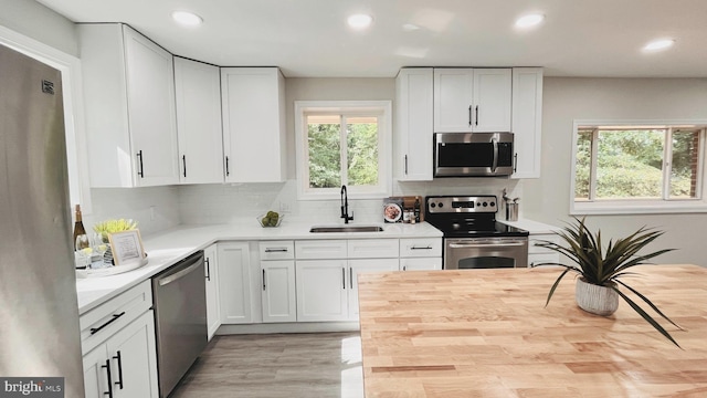 kitchen with sink, white cabinetry, tasteful backsplash, wooden counters, and appliances with stainless steel finishes