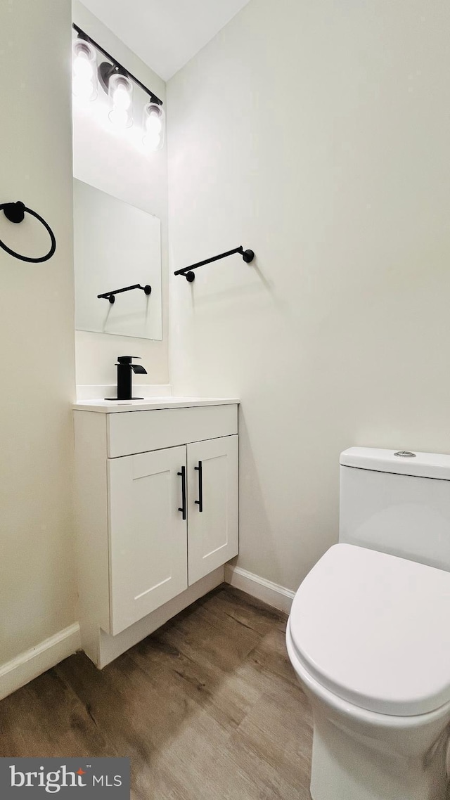 bathroom with toilet, vanity, and hardwood / wood-style flooring