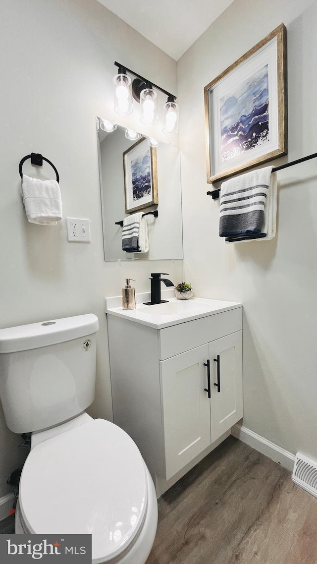 bathroom with toilet, hardwood / wood-style flooring, and vanity