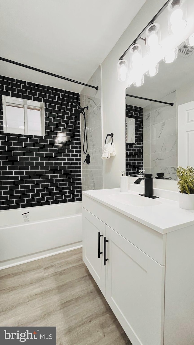 bathroom featuring tiled shower / bath combo, vanity, and wood-type flooring