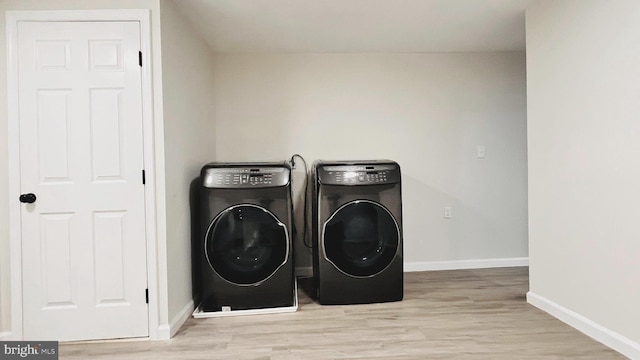 clothes washing area with washer and dryer and light wood-type flooring