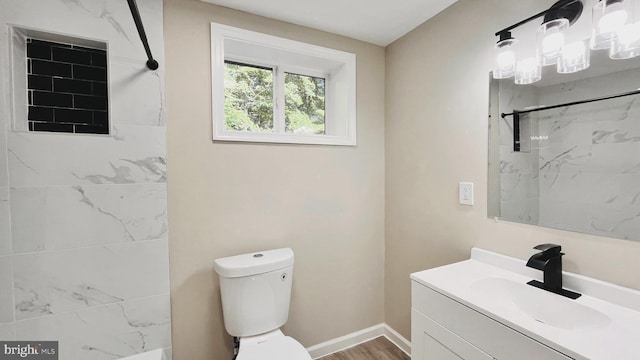 bathroom with toilet, vanity, hardwood / wood-style floors, and tiled shower