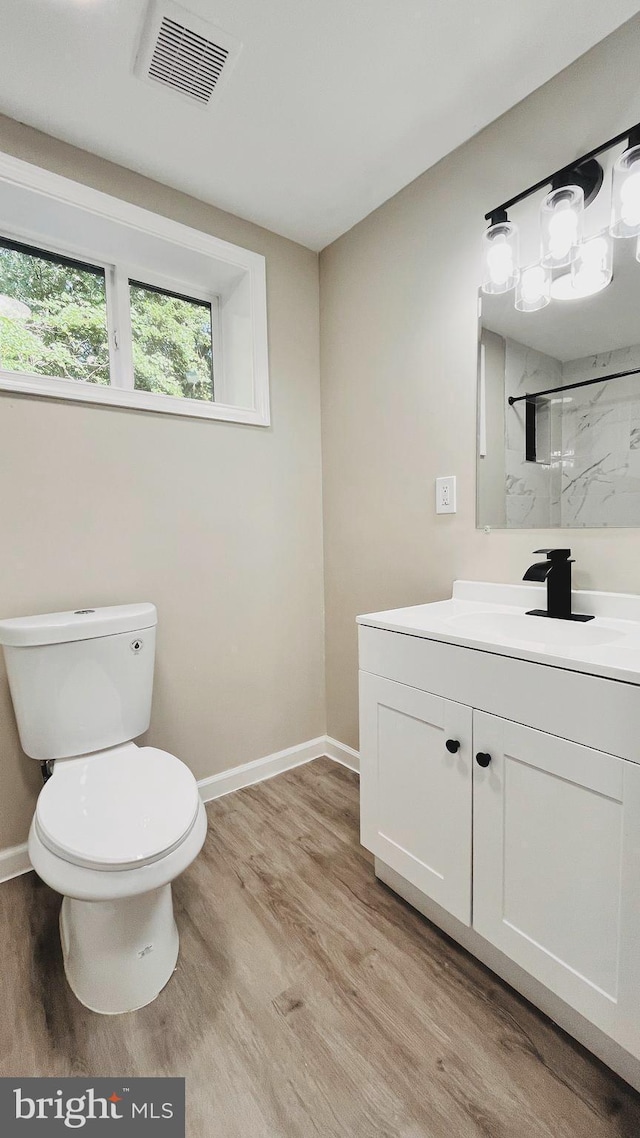 bathroom featuring toilet, hardwood / wood-style flooring, a shower, and vanity