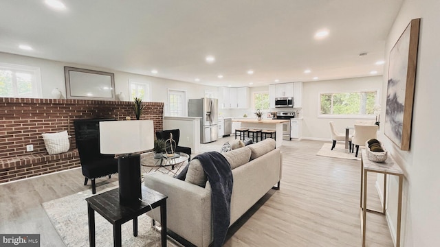 living room with brick wall, a fireplace, and light wood-type flooring