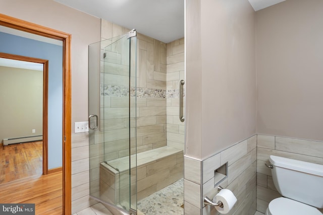 bathroom featuring hardwood / wood-style floors, toilet, tile walls, walk in shower, and a baseboard radiator