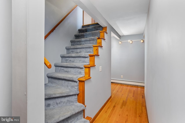 stairs with wood-type flooring and a baseboard radiator