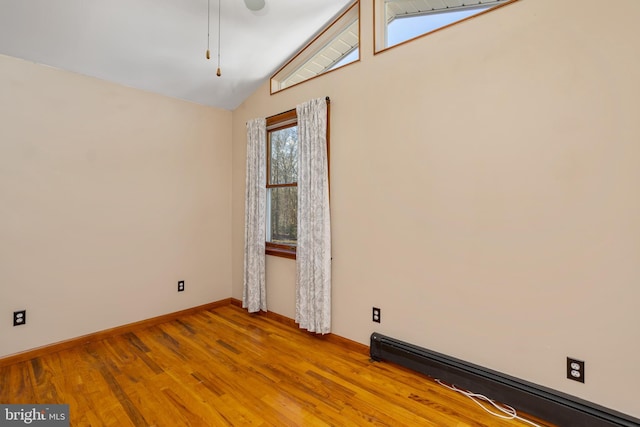 spare room featuring a baseboard radiator, vaulted ceiling, and light wood-type flooring