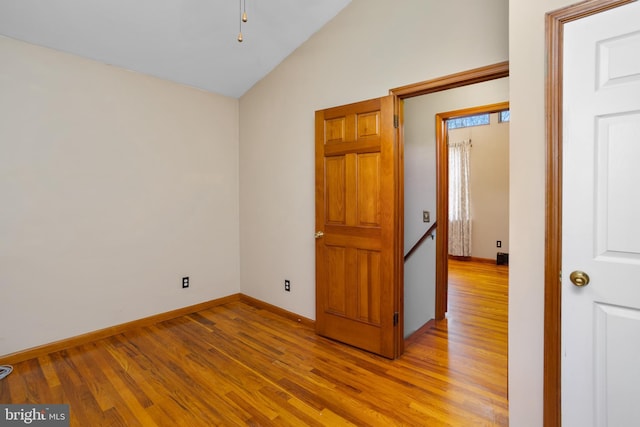 spare room featuring vaulted ceiling and light hardwood / wood-style flooring