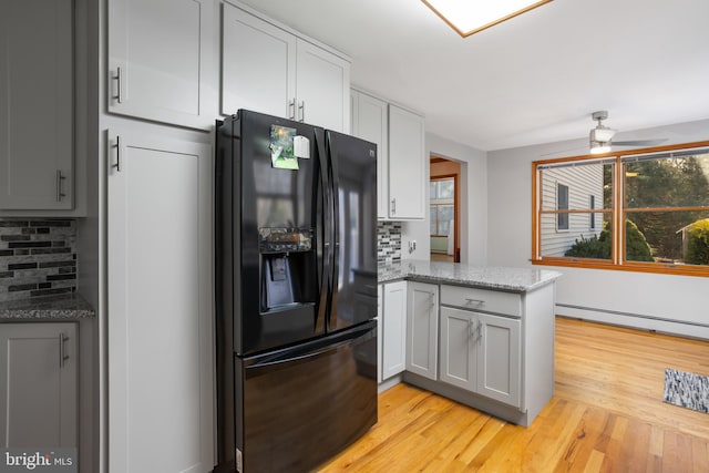 kitchen featuring black fridge with ice dispenser, backsplash, light stone counters, and ceiling fan