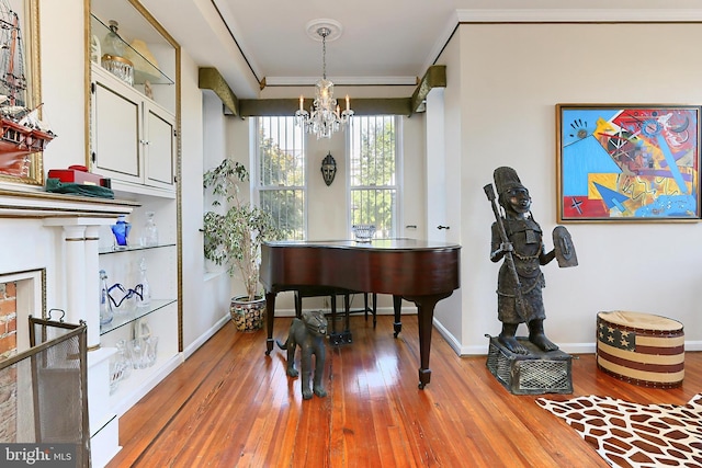 misc room with wood-type flooring, ornamental molding, and an inviting chandelier