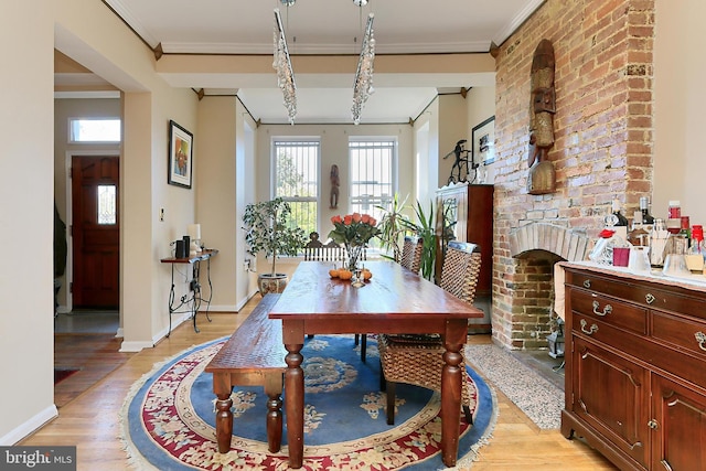 dining space with a fireplace, light wood-type flooring, and crown molding