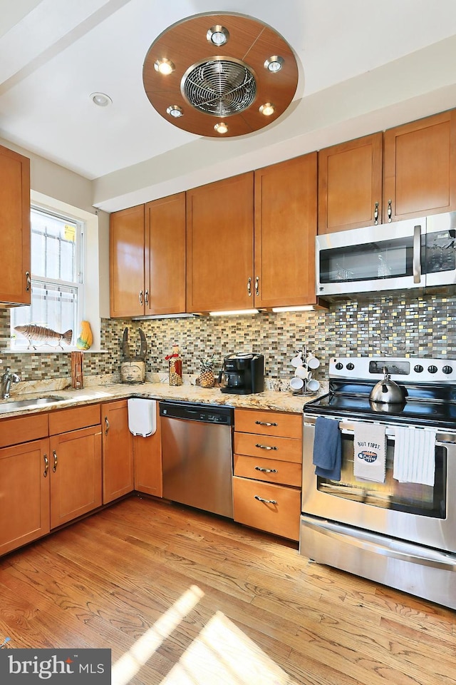 kitchen featuring appliances with stainless steel finishes, backsplash, light hardwood / wood-style flooring, and sink