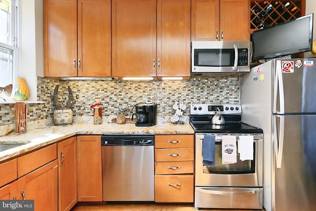 kitchen with light stone countertops, backsplash, and appliances with stainless steel finishes