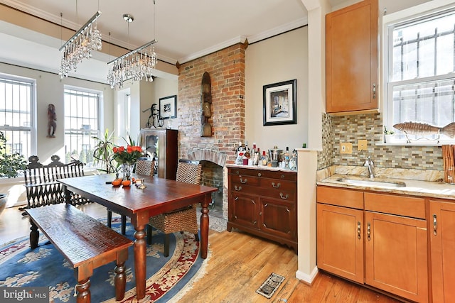 dining room with sink, ornamental molding, and light wood-type flooring