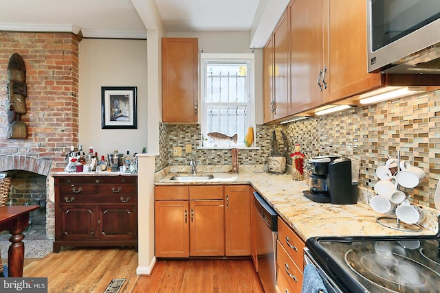 kitchen with decorative backsplash, appliances with stainless steel finishes, light hardwood / wood-style flooring, and light stone counters