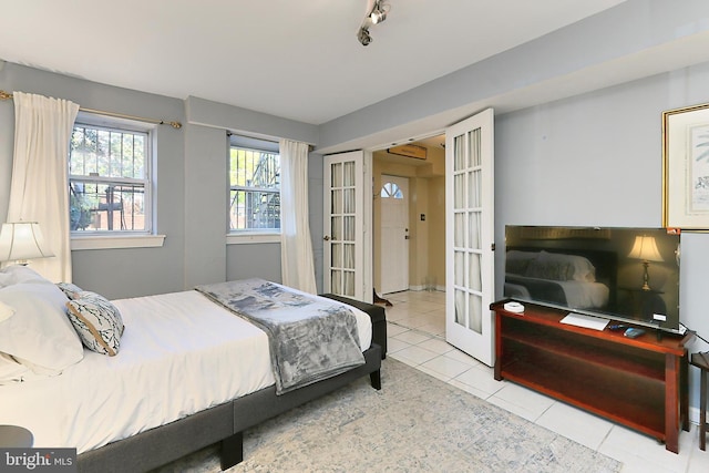 bedroom featuring track lighting, light tile patterned floors, and french doors