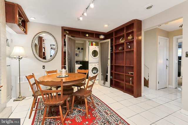 dining area featuring stacked washer / dryer, light tile patterned floors, and track lighting