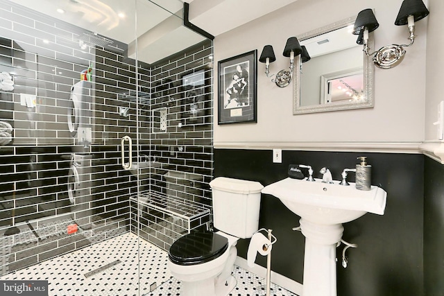 bathroom featuring tile patterned flooring, toilet, and tiled shower