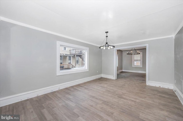 unfurnished dining area featuring crown molding, hardwood / wood-style floors, and a notable chandelier