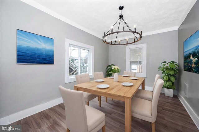 dining area featuring dark hardwood / wood-style floors, crown molding, and an inviting chandelier