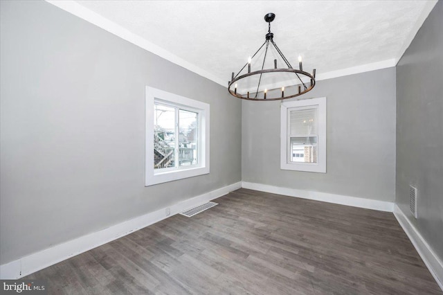 spare room with ornamental molding, dark hardwood / wood-style flooring, a textured ceiling, and a notable chandelier