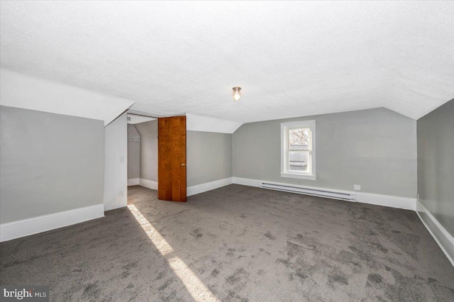 additional living space featuring dark colored carpet, a textured ceiling, baseboard heating, and lofted ceiling
