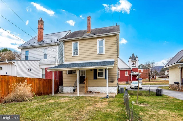 rear view of house featuring a lawn and central AC unit