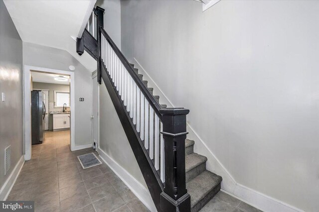 stairway featuring sink and tile patterned flooring