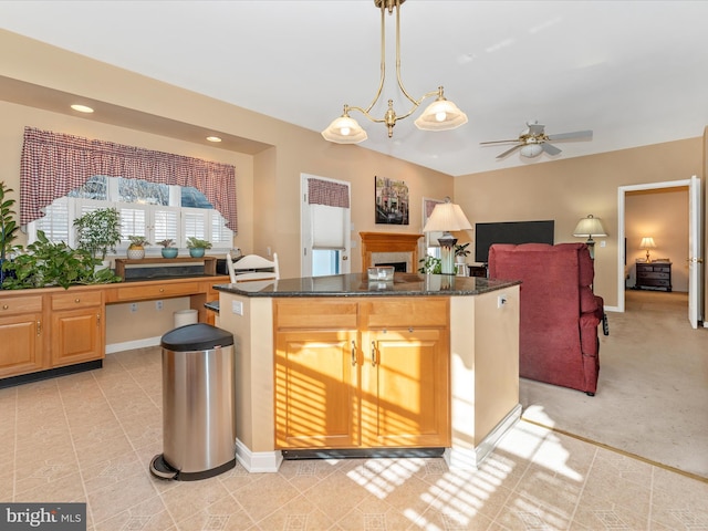 kitchen with dark stone countertops, hanging light fixtures, ceiling fan, and a kitchen island