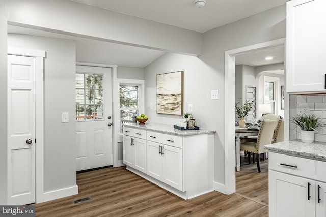 bar featuring white cabinets, decorative backsplash, and light stone counters