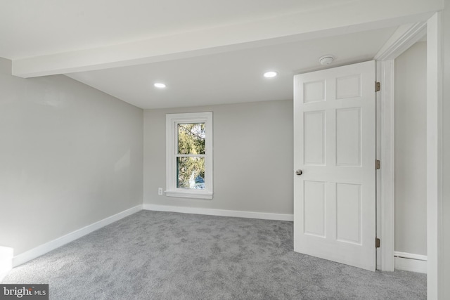 empty room featuring beam ceiling and light colored carpet